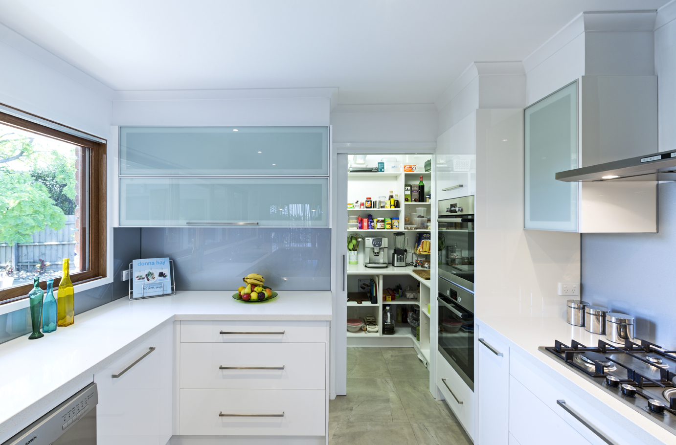 white kitchen with sliding door leading to extra storage room