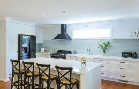 white kitchen with island and stools at a breakfast bar