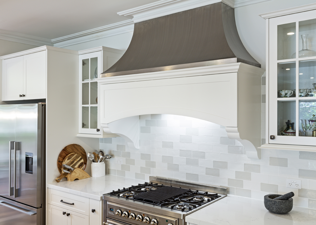 white kitchen with stovetop and large exhaust hood